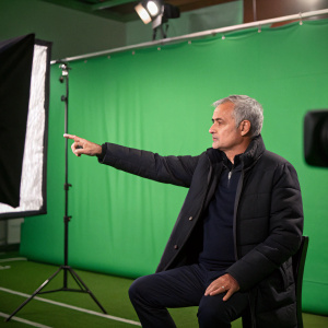Jose Mourinho, former football manager, in a tense interview. Caucasian, dark jacket, extended arm. Backdrop: green screen