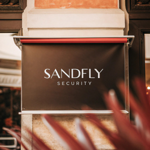 Modern logo for a security company, 'Sandfly Security', trademarked. Design includes sleek font on black backdrop