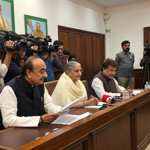 Press conference featuring politicians Ghulam Nabi Azad, Sheila Dikshit, and Raj Babbar. They are seated behind a long table discussing policy issues. A sea of journalists with notepads and cameras fill the room.