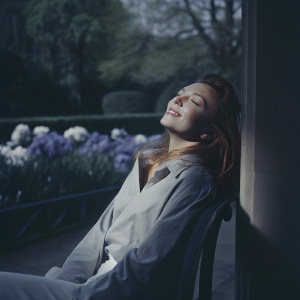 Natalie Dormer in a candid moment, natural lighting, serene outdoor setting.