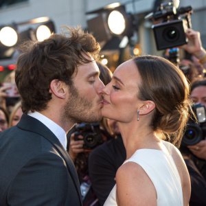Sam Claflin and Laura Haddock caught in a passionate kiss amidst a bustling crowd at a celebrity award show.