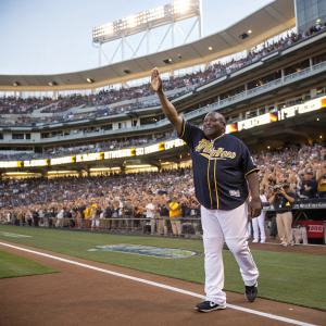Retirement ceremony for Tony Gwynn. Wearing a dark Padres jersey and white pants. Waves to the cheering crowd. Large stadium filled with fans