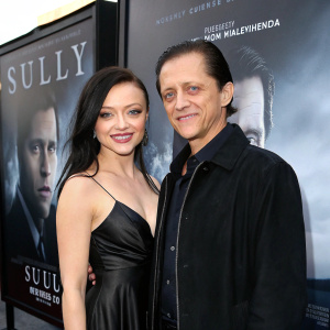 Francesca Eastwood and Clifton Collins Jr. at the 'Sully' premiere. Francesca in a black gown, Clifton in a dark jacket. They stand close, smiling warmly. Movie poster in the background.