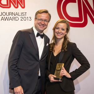Fritz Meinikat and Nina Eichinger, winners of CNN Journalist Award 2013, posing in front of CNN logo backdrop. Both wear formal attire.