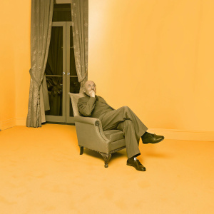 Vladimir Nabokov, sitting in an elegant armchair, against a luxurious hotel room background. The scene is in black and white