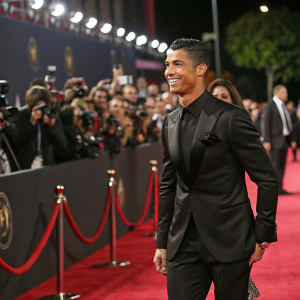 Cristiano Ronaldo in a sleek black suit at a glamorous award ceremony, surrounded by cheering fans and flashing cameras.
