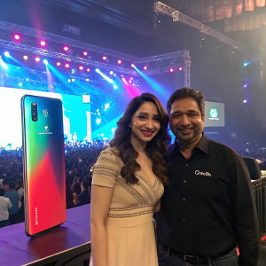 Tamannaah Bhatia and Murali Retineni at a bustling tech conference. Vibrant stage setup with Celkon Octa Core 510 phone prominently displayed. Energetic crowd in the background.