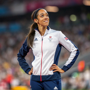 Katarina Johnson-Thompson, Olympic athlete, posing confidently. Wearing a Team GB tracksuit. Background is blurred crowd at sports event.