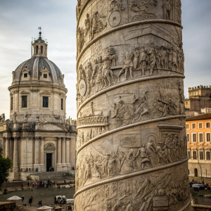 Detail of Trajan's Column in Rome. Historical event depicted with many figures in different poses, carved intricately. Stone tones and muted color palette. Architectural backdrop.