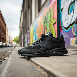 Black Nike Air Max sneaker with mesh-like texture. Posing on an urban street with a graffiti wall background.