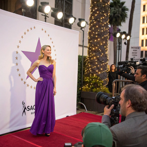 Caucasian actress at the Hollywood Walk of Fame unveiling. Purple dress, white logo backdrop, red carpet event.