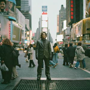 Wax statue of Tom Cruise in Times Square. Amidst crowd of tourists and visitors. Vibrant city lights and signs in background.