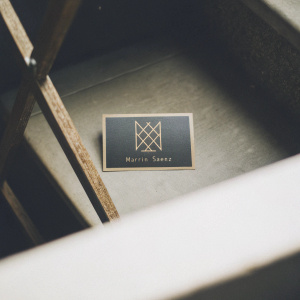 Business card design for Martin Saenz, featuring a minimalist logo of intersecting golden lines on a dark blue backdrop. Includes QR code for portfolio access, alongside contact details in a clean, modern font.
