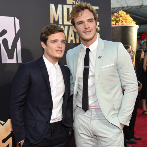 Josh Hutcherson and Sam Claflin attend the MTV Movie Awards, standing confidently in front of the iconic MTV logo backdrop.