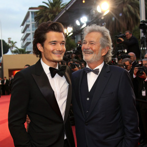 Orlando Bloom and Bob Shaye at a high-profile awards ceremony. Red carpet event, surrounded by photographers and fans.