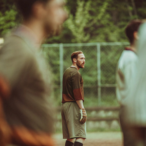 Jan Oblak, standing on a field, intense look on his face. Wearing his team's uniform, blurred green backdrop