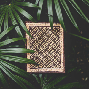 A detailed, richly textured, woven rattan mat showcasing an intricate diamond pattern. The mat boasts a deep brown hue, perfect for adding warmth to any room.