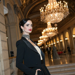 Krysten Ritter at a charity gala. Formal attire, elegant pose. Chandeliers and grand architecture in the background.