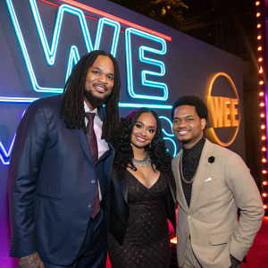 Waka Flocka and Charlie Rivera with Tammy Rivera. They are attending a WE tv award show, standing in front of a neon-lit promotional backdrop.