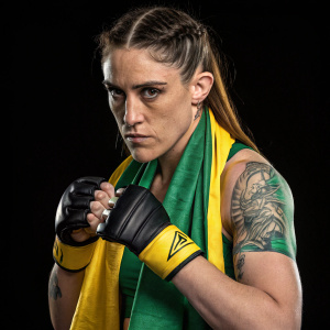 Megan Anderson, serious face, athletic build. Wearing green and yellow boxing gear. Solo shot, plain black background