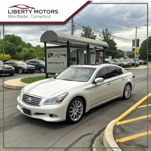 Listing for a used Infiniti M35, parked at Liberty Motors in Manchester, Connecticut. The car's front profile highlights its sleek design and Infiniti logo. Dealership's website and contact details are displayed. Background includes a busy parking lot and a nearby bus stop.