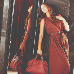 Lisa Ray, a model with long brown hair, poses elegantly. Wearing a simple brown dress. Against a sleek black backdrop with sharp focus on her.