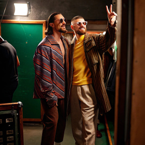Zlatan Ibrahimovic and Ante Rebic, wearing casual outfits, standing together in a backstage area. Zlatan gives peace sign, Ante has beard. Candid photo.