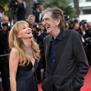 Rebecca De Mornay and Harry Dean Stanton laughing at the film festival. Red carpet event with flashing cameras