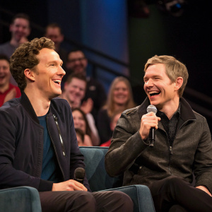 Benedict Cumberbatch and Martin Freeman sharing a laugh during the Sherlock reunion panel. Studio audience in the background.