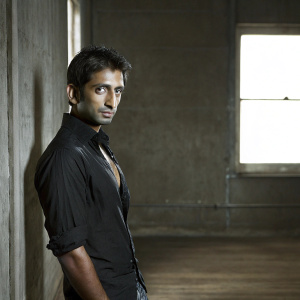 Close-up of Narayan Karthikeyan, Indian actor, intense gaze. Dark background. Soft lighting highlights his sharp features and black shirt