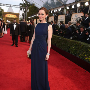 Alexis Bledel, elegant and poised, wearing a floor-length navy blue dress at the Golden Globe Awards. Crowded and vibrant red carpet setting.