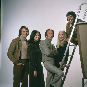 The cast of 'Three's Company', including John Ritter, Joyce DeWitt, Don Knotts, Priscilla Barnes, Jenilee Harrison, and Richard Kline, pose for a publicity still in casual attire. Cheerful expressions. Blue studio backdrop