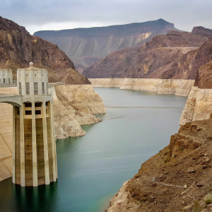 The Hoover Dam, an iconic engineering marvel, stands tall against the dramatic backdrop of the Black Canyon in Nevada. The expansive Lake Mead, with its striking turquoise waters, sprawls below. Surrounded by rugged cliffs and jagged mountain peaks, this awe-inspiring site is a testament to human ingenuity.