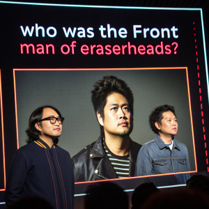 Digital screen showcasing Eraserheads band members Bamboo Manalac, Eli Buendia, and Chito Miranda. Dark background with neon accents. Text overlay: 'Who was the Front Man of Eraserheads?'