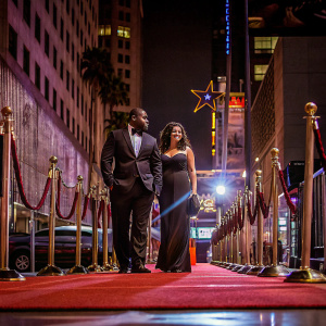 Reggie Bush and Lilit Avagyan on the golden Hollywood Walk of Fame. Formal attire, standing on the vibrant red carpet.