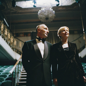 Midge Ure and Flossie Ure at a gala event. Black tie affair with chandelier lighting. Elegant ballroom backdrop