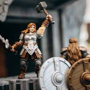 Brigitte, Overwatch character, in her Shieldmaiden skin. Detailed armor and accessories. One figure mid-air, other standing assertively. Dark gray background, game scene