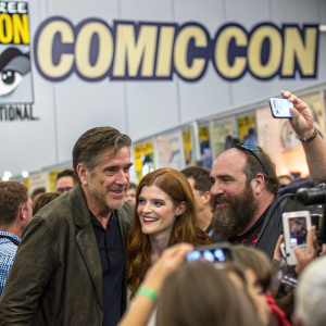 Craig Ferguson, Rose Leslie, and Rory McCann at a bustling Comic-Con event. Prominent Comic-Con logos on backdrop