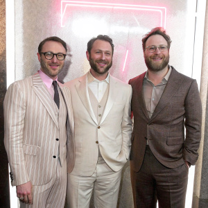 Charlie Collier, Evan Goldberg, and Seth Rogen at 'Preacher' season two premiere. Formal attire, smiling, against neon-lit promotional backdrop.