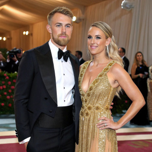 Aaron Ramsey and Colleen Rowland attending the Met Gala. Aaron in a sharp tuxedo, Colleen in a stunning gold gown with intricate beading.