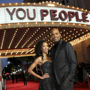 Boris Kodjoe and Sophie Tei Naaki Lee Kodjoe at a glitzy Hollywood event. They pose in front of a grand, illuminated backdrop featuring the film 'You People'.
