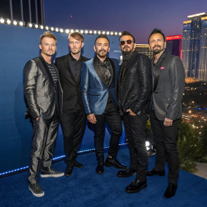 Backstreet Boys members Brian Littrell, Nick Carter, AJ McLean, Howie Dorough, and Kevin Richardson, dressed in sleek suits, pose at the Billboard Music Awards. Blue backdrop, glitzy stage, Las Vegas