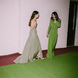 Selena Gomez and Victoria Justice, both in evening gowns, at a star-studded awards ceremony. Crowded venue with flashing lights.