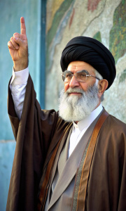 Ali Khamenei. Strong and wise. Pointing up. Against the background of the wall. We see him in full height.