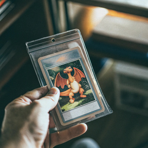 Close-up of a Pokémon card featuring Charizard. The card is encased in a clear plastic protective sleeve. Warm, vibrant background colors. Excellent condition.