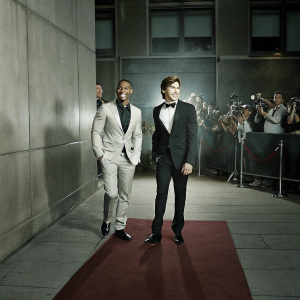 Michael B. Jordan and Zac Efron smiling at a movie premiere event. Crowded and vibrant red carpet scene.