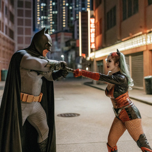 Batman and Harley Quinn dueling in the neon-lit streets of Gotham City at night.