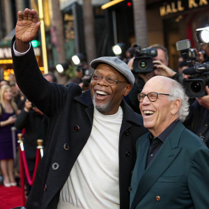 Samuel L. Jackson and Irwin Winkler attending a premiere. On the Hollywood Walk of Fame, surrounded by flashing cameras and paparazzi. They are smiling and waving. Grauman's Chinese Theatre in the background.
