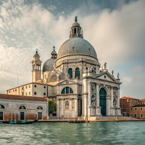 Imposing image of Church Santa Maria del Rosario. Grand white structure with intricate decorations. Situated on tranquil waters reflecting its majestic dome and statues. Classic architecture with a grand entrance.