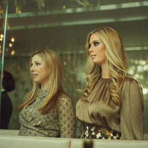 Chelsea Clinton and Ivanka Trump, with flowing blonde hair, at L'Oréal Paris event. White and gold backdrop.